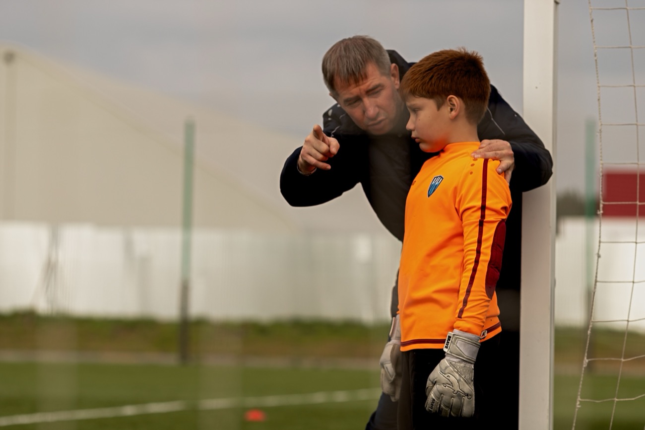 Coach kneeling to speak with a player