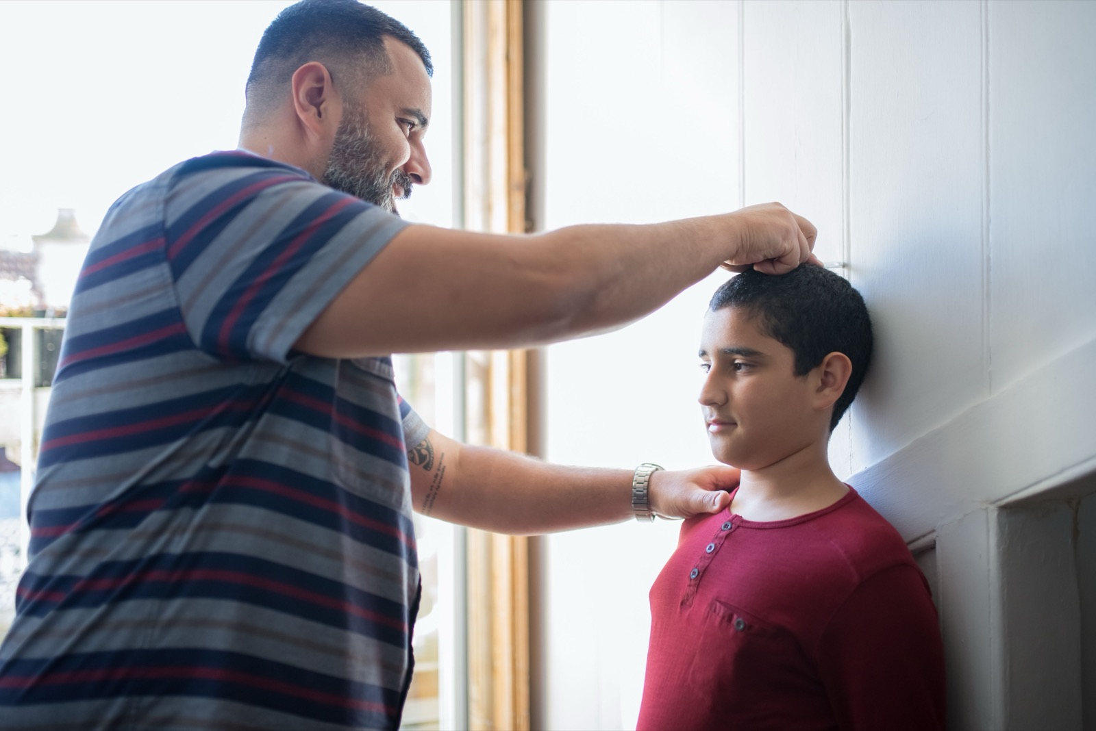 Adolescent measuring height during a growth spurt